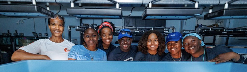 A proud moment for coral conservation: Scientists from Perry Institute for Marine Science, Atlantis, and partner organizations stand over the newly established coral gene bank at Atlantis Paradise Island, having just populated its tanks with rescued coral colonies. Photo: Atlantis Paradise Island