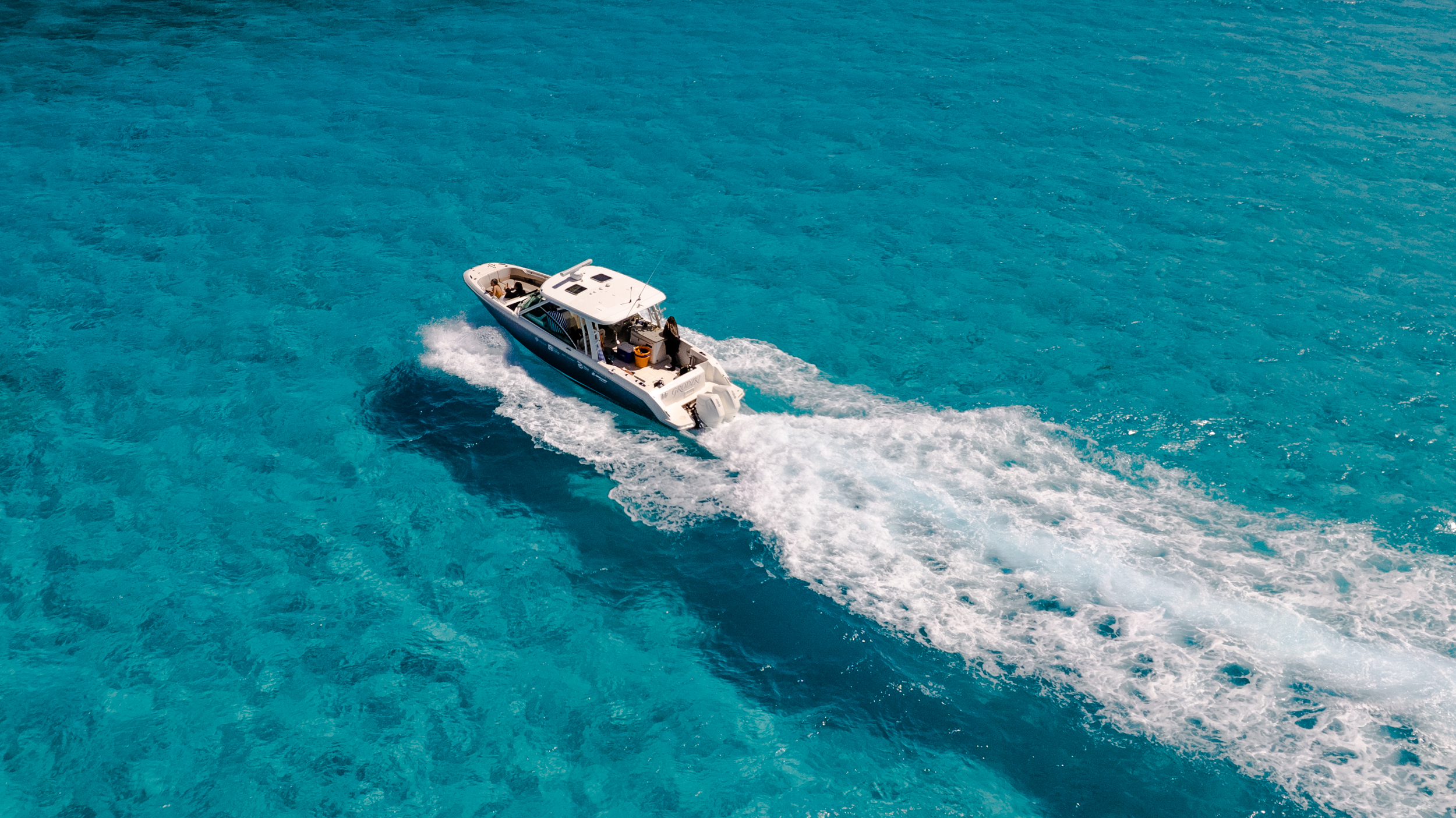 Aerial drone shot of PIMS research vessel Grodzki cruising over turquoise Bahamian water near Nassau.