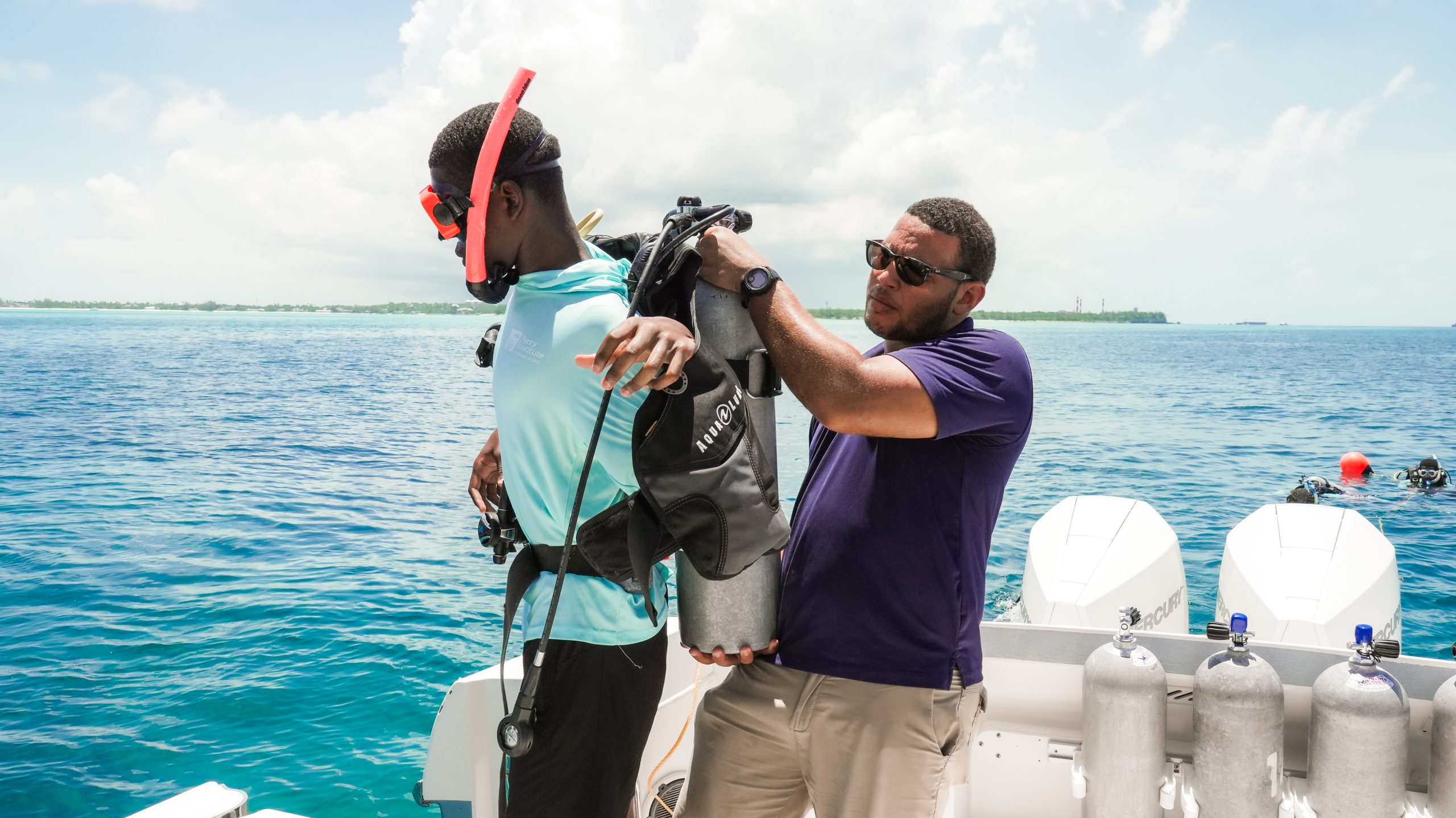 PIMS instructor helps a trainee fit a scuba tank aboard the research vessel Grodzki.