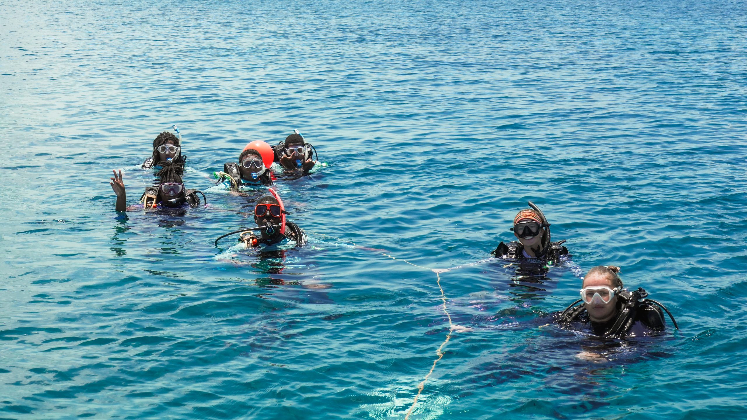 Coral restoration trainees grouped at the surface during a dive briefing in Nassau.